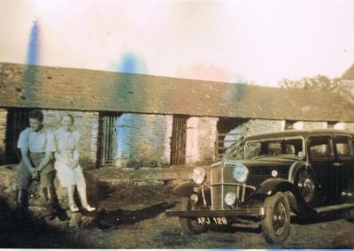 Cowshed at Lower House Farm with John Francis and Molly Tucker sitting with a car Morris Oxford, registration AFJ 129. Laid up in the Town Linhay during the war but various children wrecked it
